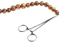 Hemostat clamped onto end of stringed beads